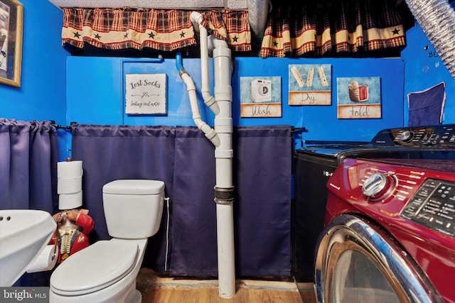 bathroom featuring separate washer and dryer, wood finished floors, and toilet