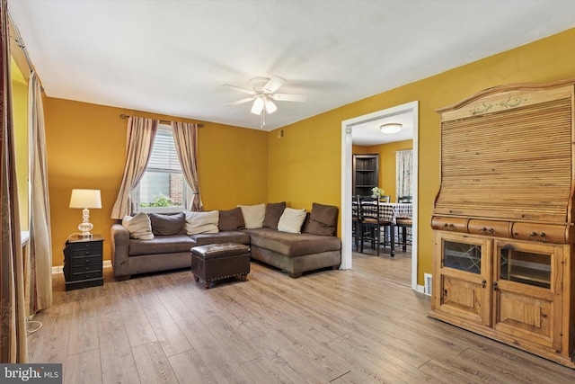 living room featuring ceiling fan, hardwood / wood-style flooring, and baseboards