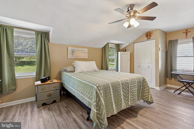 bedroom with baseboards, wood finished floors, lofted ceiling, and ceiling fan