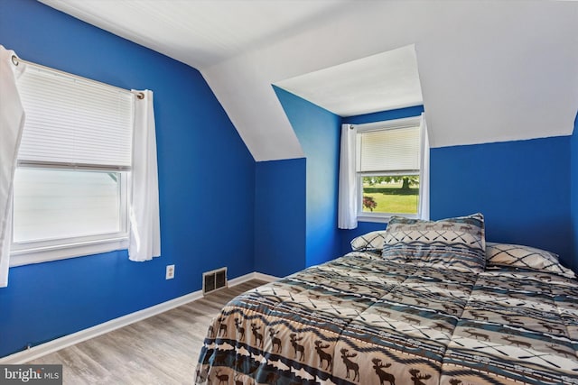 bedroom featuring lofted ceiling, wood finished floors, and baseboards