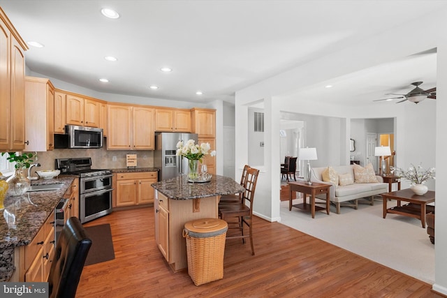 47433 River Crest St, Sterling, VA 20165 - kitchen with stainless steel appliances, a sink, light brown cabinets, a breakfast bar, and a center island