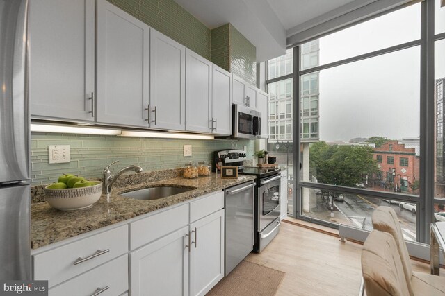 1414 Belmont St NW Unit 207, Washington, DC 20009 - kitchen featuring a sink, stainless steel appliances, decorative backsplash, stone countertops, and a wall of windows