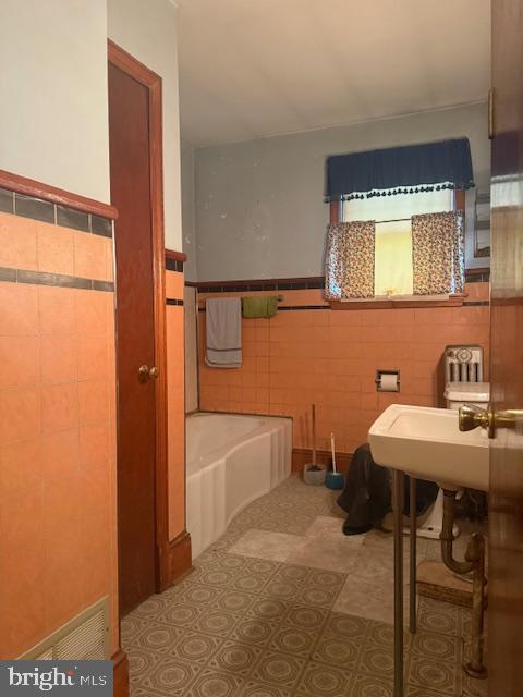 110 N Main St, Union Bridge, MD 21791 - bathroom with tile walls, a bath, and a wainscoted wall