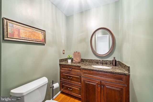 bathroom featuring toilet, vanity, and wood finished floors