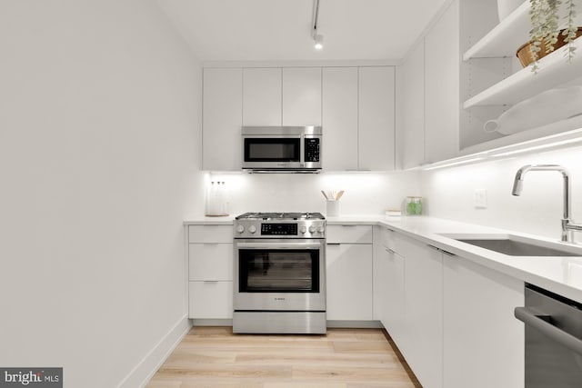 kitchen featuring appliances with stainless steel finishes, a sink, white cabinetry, and light countertops