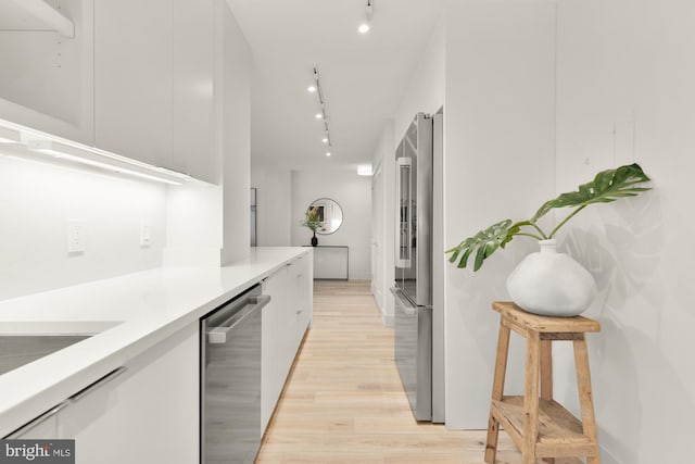 kitchen featuring appliances with stainless steel finishes, track lighting, modern cabinets, light wood-style floors, and light countertops