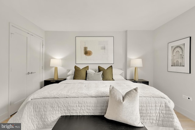 bedroom featuring wood finished floors, baseboards, and a closet