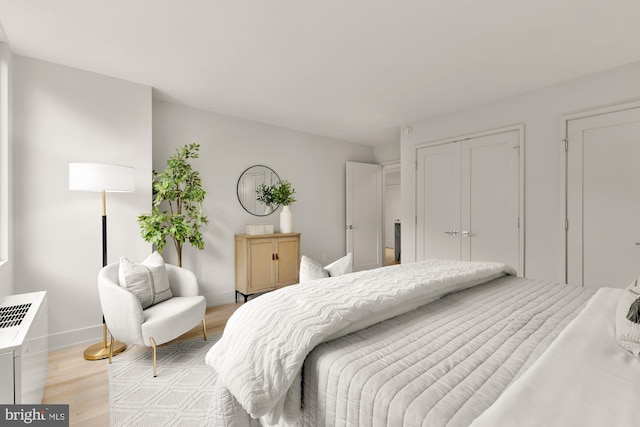 bedroom with light wood-style flooring, baseboards, and a closet