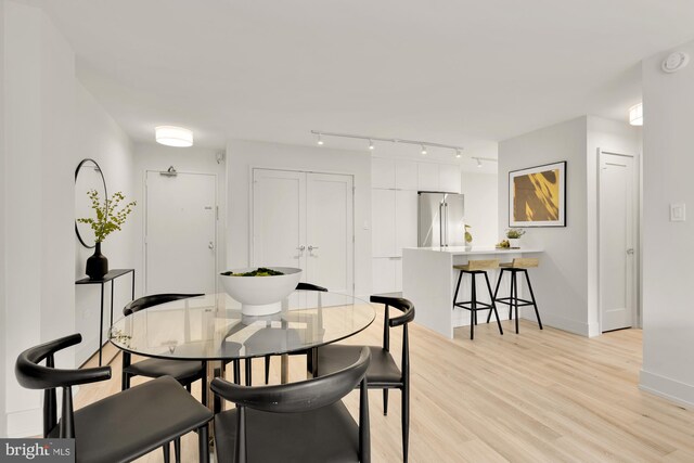 dining area with light wood-style floors, rail lighting, and baseboards