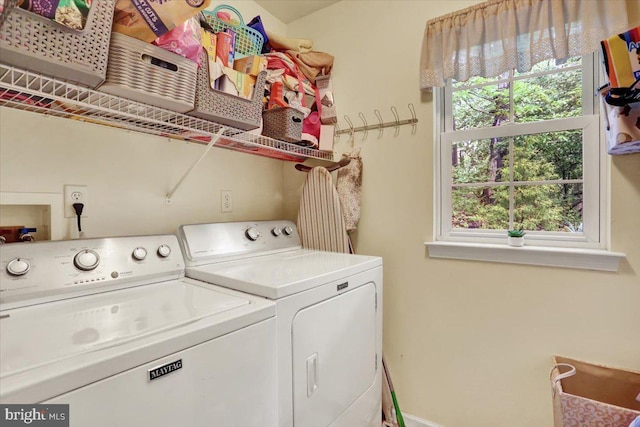 clothes washing area featuring washing machine and dryer, healthy amount of natural light, and baseboards