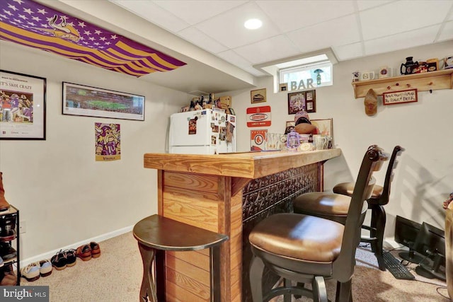 indoor dry bar featuring freestanding refrigerator, carpet floors, baseboards, and a drop ceiling