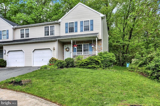 traditional-style home featuring a garage, asphalt driveway, a porch, and a front lawn