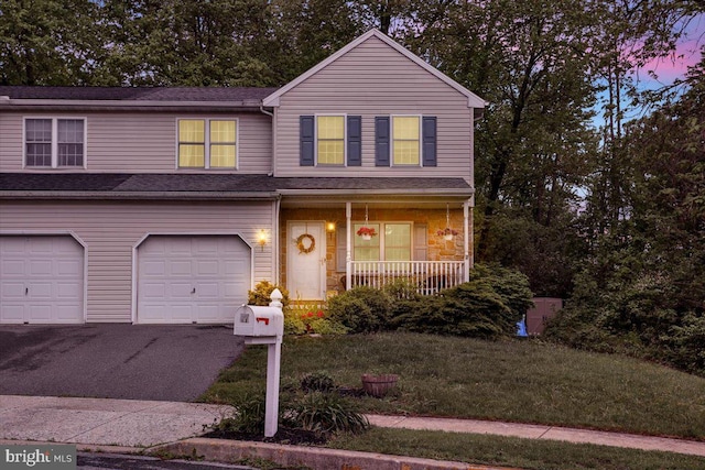 traditional-style house with a porch, a garage, and asphalt driveway