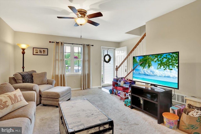 living area with a ceiling fan, stairway, carpet, and baseboards