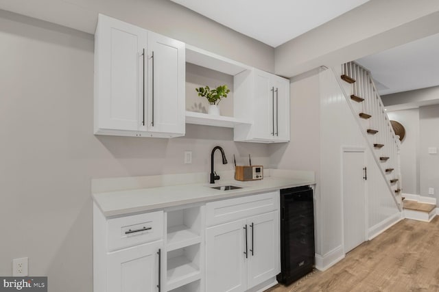 7603 Hammond Ave, Takoma Park, MD 20912 - kitchen featuring open shelves, beverage cooler, white cabinetry, light wood-style floors, and a sink