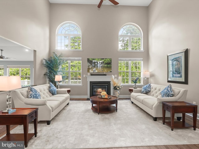 8484 Oak Run Way, Ellicott City, MD 21043 - living area featuring a ceiling fan, a high ceiling, plenty of natural light, and a glass covered fireplace