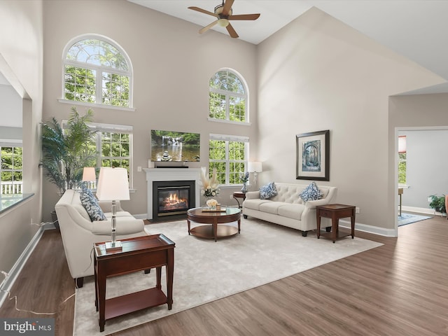 8484 Oak Run Way, Ellicott City, MD 21043 - living area with ceiling fan, wood finished floors, a high ceiling, a fireplace with flush hearth, and plenty of natural light