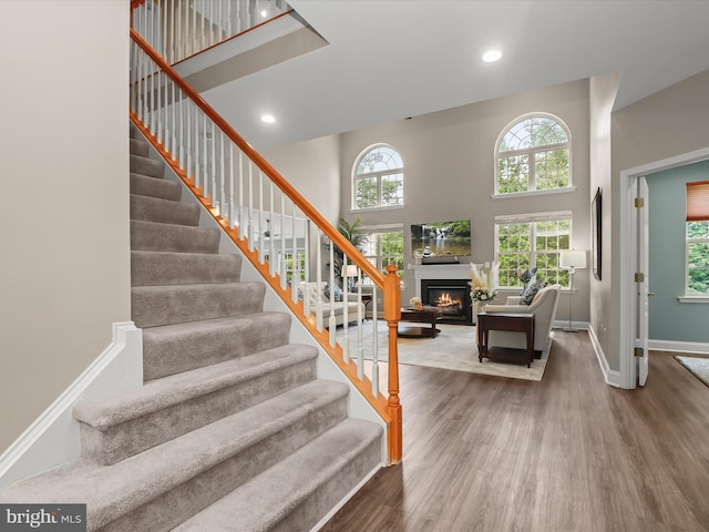 8484 Oak Run Way, Ellicott City, MD 21043 - stairs featuring a towering ceiling, wood finished floors, a glass covered fireplace, recessed lighting, and baseboards