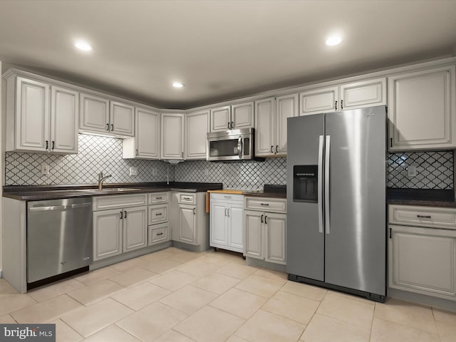 8484 Oak Run Way, Ellicott City, MD 21043 - kitchen featuring appliances with stainless steel finishes, dark countertops, a sink, decorative backsplash, and recessed lighting