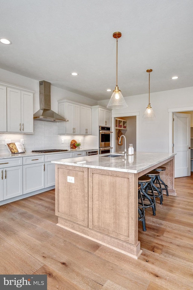 101 Eagle Dr, Broomall, PA 19008 - kitchen featuring wall chimney range hood, a sink, appliances with stainless steel finishes, light wood-type flooring, and white cabinetry