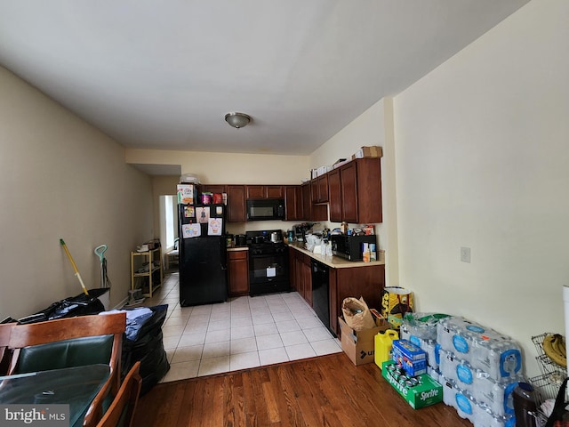kitchen with black appliances, light wood-type flooring, and light countertops
