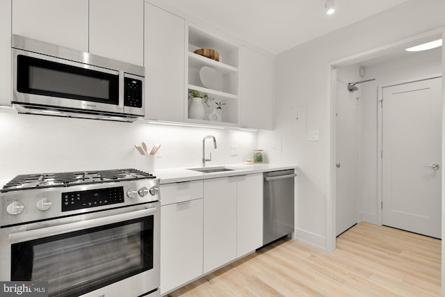 2939 Van Ness St NW Unit 424, Washington, DC 20008 - kitchen with appliances with stainless steel finishes, a sink, light wood finished floors, white cabinets, and light countertops
