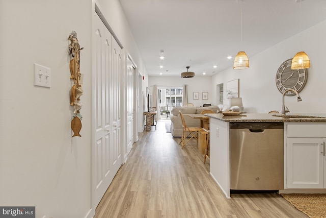 kitchen featuring dishwasher, light wood-style flooring, a sink, white cabinets, and pendant lighting