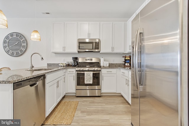 kitchen with appliances with stainless steel finishes, a sink, a peninsula, and white cabinets