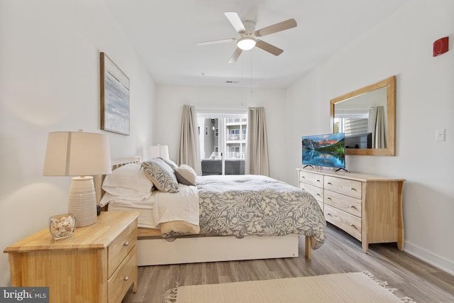 bedroom with multiple windows, light wood-type flooring, baseboards, and ceiling fan