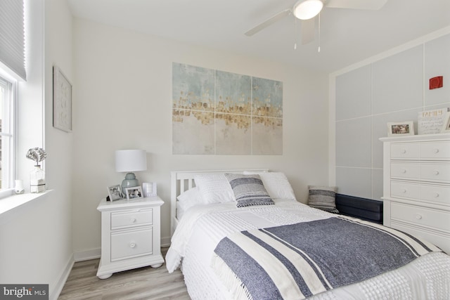bedroom featuring light wood-style flooring, a ceiling fan, and baseboards