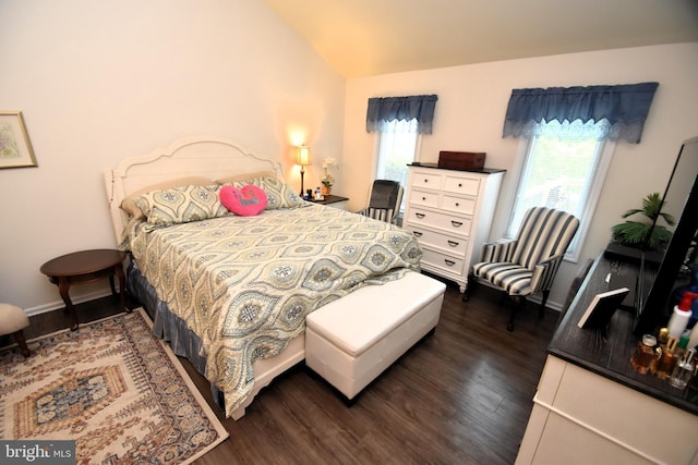bedroom with vaulted ceiling, dark wood finished floors, and baseboards