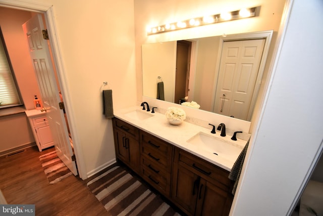bathroom with wood finished floors, double vanity, and baseboards