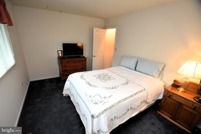 bedroom with dark carpet and baseboards