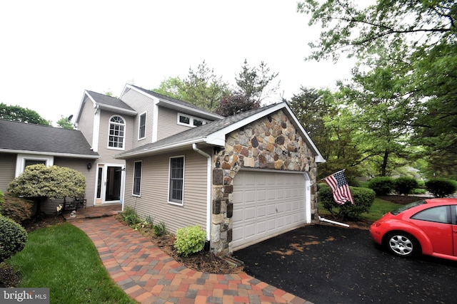 view of home's exterior featuring stone siding, asphalt driveway, and a garage