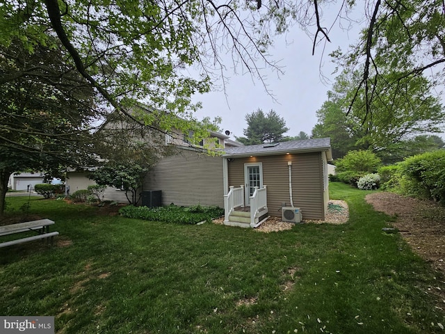 back of house featuring a lawn, a cooling unit, and central AC unit