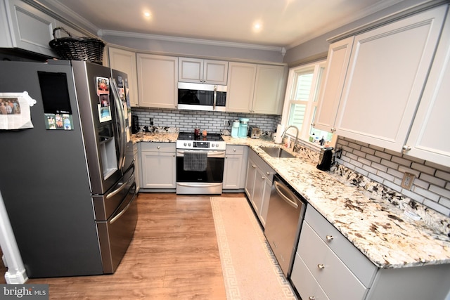 kitchen featuring stainless steel appliances, gray cabinetry, tasteful backsplash, a sink, and crown molding