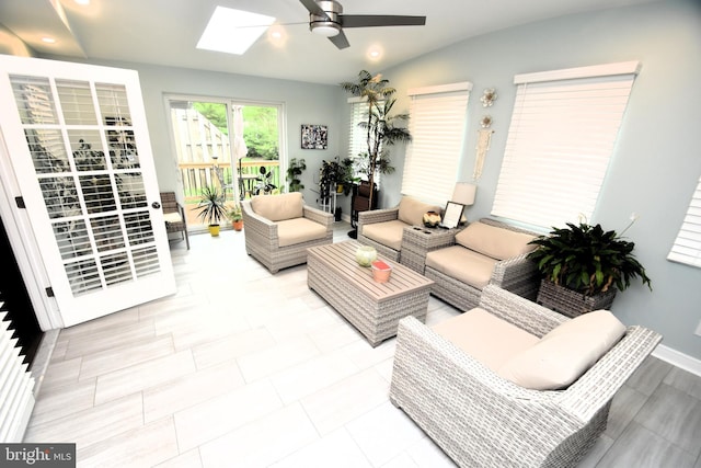 living area featuring a ceiling fan, a skylight, baseboards, and recessed lighting
