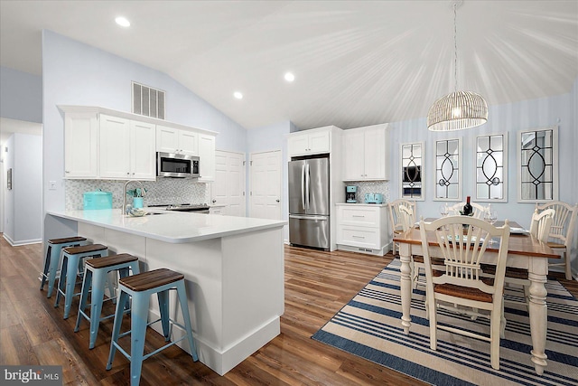 4 Abbey Cir, Ocean Pines, MD 21811 - kitchen with appliances with stainless steel finishes, lofted ceiling, white cabinetry, decorative backsplash, and a breakfast bar