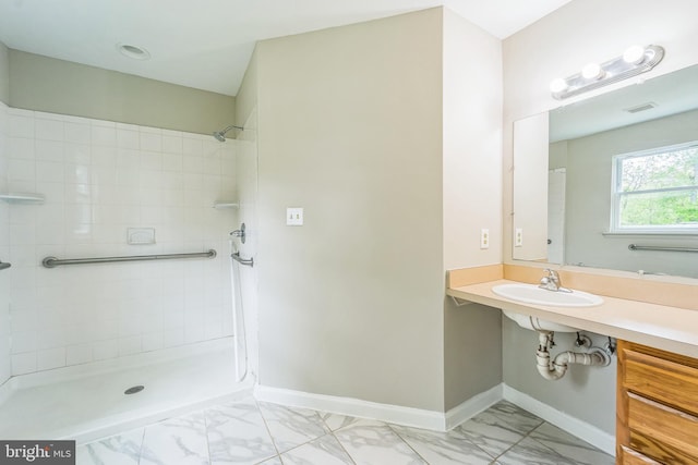 full bath featuring marble look tile flooring, a tile shower, and baseboards