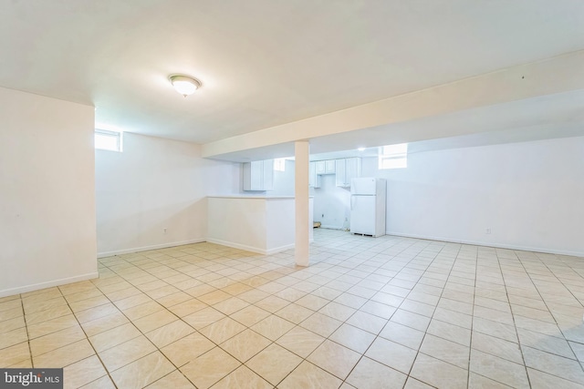 basement featuring freestanding refrigerator and baseboards