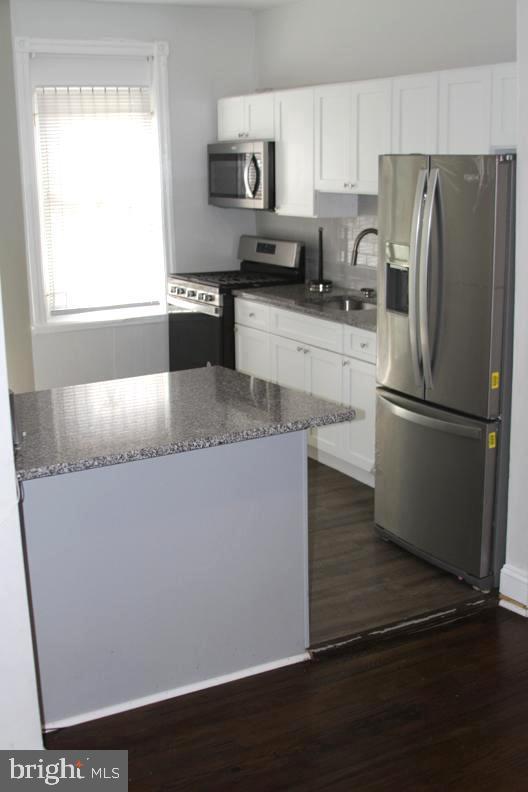 126 N Sickels St, Philadelphia, PA 19139 - kitchen featuring appliances with stainless steel finishes, a sink, white cabinetry, and dark wood-style flooring