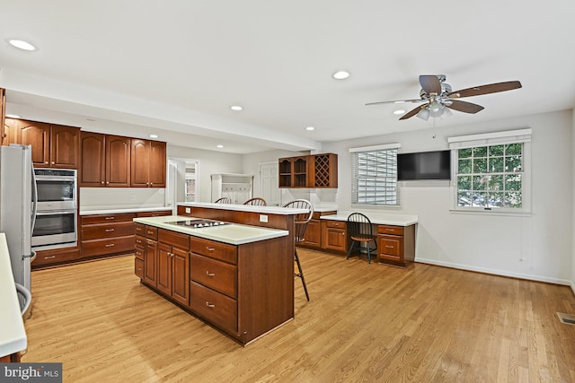 11904 Paradise Ln, Herndon, VA 20171 - kitchen featuring appliances with stainless steel finishes, a breakfast bar area, light wood-style floors, ceiling fan, and a kitchen island