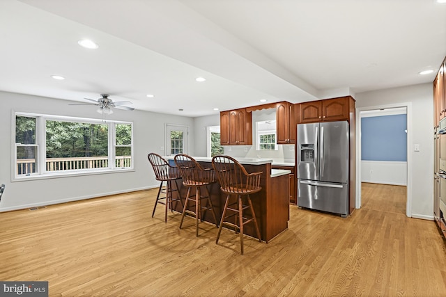 11904 Paradise Ln, Herndon, VA 20171 - kitchen with stainless steel fridge, a breakfast bar area, light wood-style flooring, baseboards, and recessed lighting