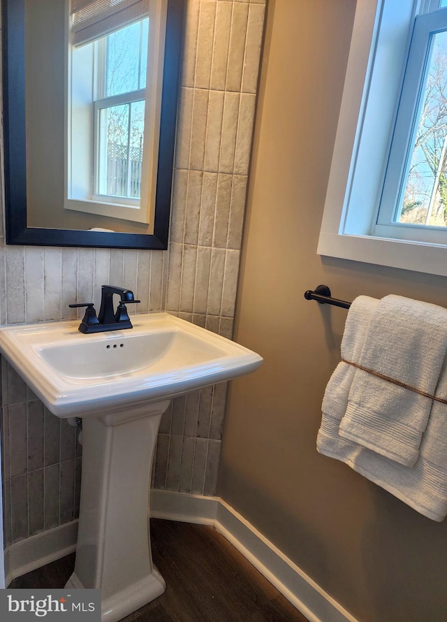 bathroom with healthy amount of natural light, a sink, wood finished floors, and baseboards