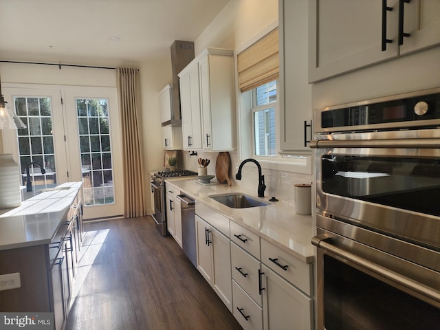 kitchen featuring a sink, appliances with stainless steel finishes, light countertops, white cabinets, and dark wood finished floors