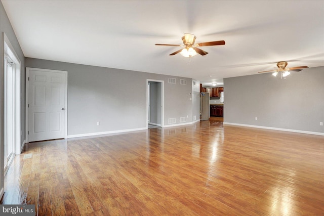 unfurnished living room with ceiling fan, light wood finished floors, and baseboards