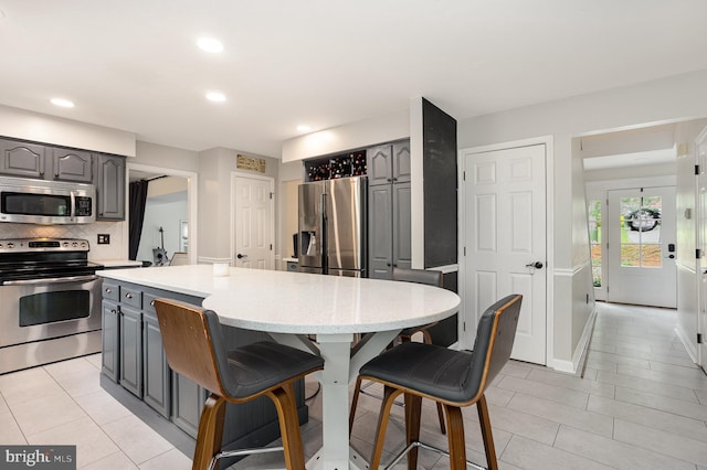 1015 E Macphail, Bel Air, MD 21015 - kitchen featuring appliances with stainless steel finishes, gray cabinets, a breakfast bar, a center island, and tasteful backsplash