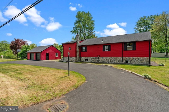 view of front of property featuring a detached garage, a front lawn, and a chimney
