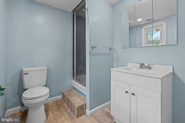 bathroom featuring a textured ceiling, wood finished floors, toilet, a shower stall, and vanity