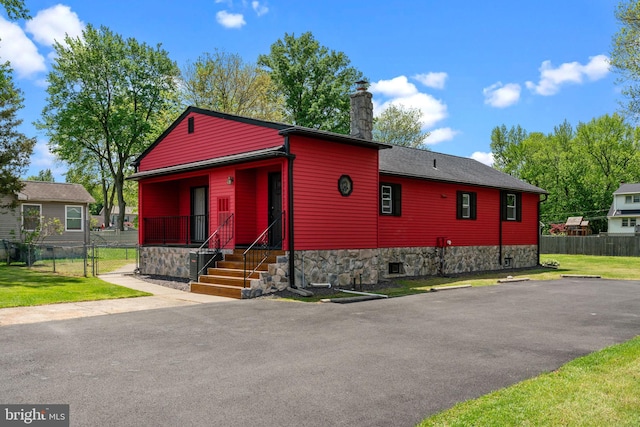 view of front facade with covered porch, a chimney, and a gate